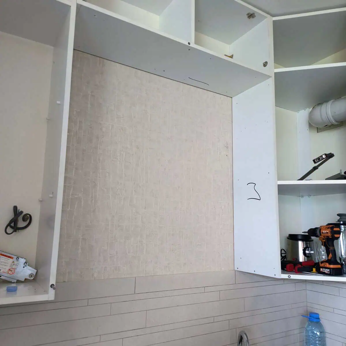 Master loosens kitchen cabinet fixings to access the dish rack in Tbilisi