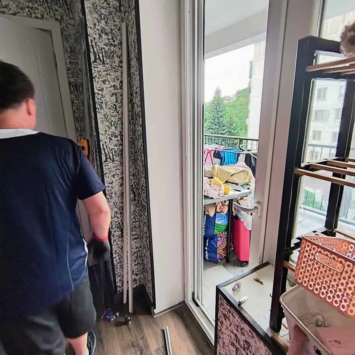 Мастер CityHandyman снимает стеклопакет с рамы балконной двери ПВХ в квартире в Тбилиси