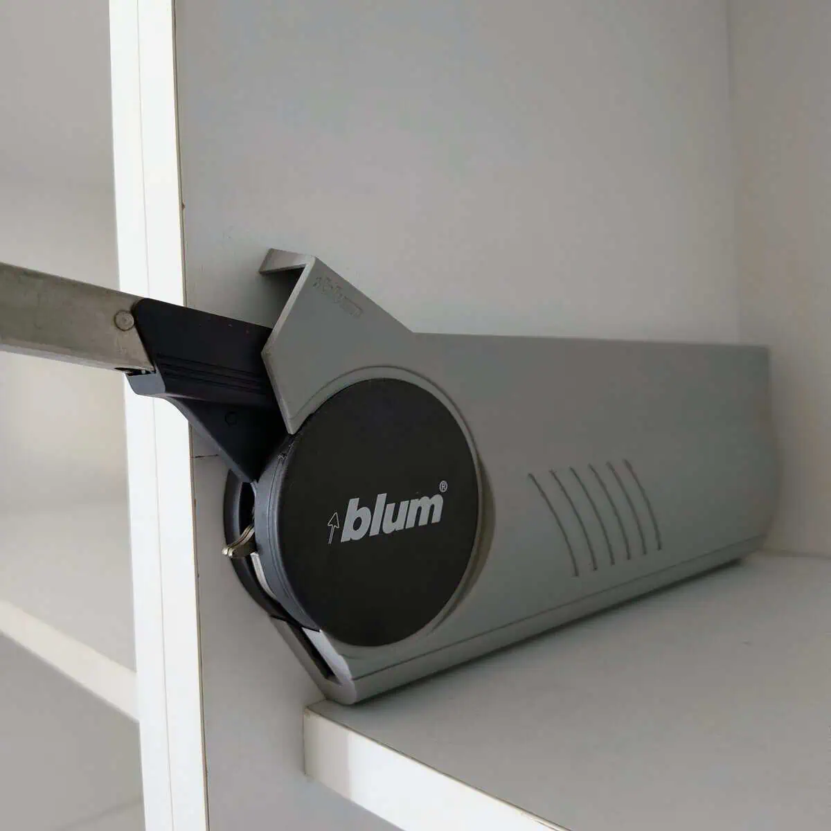 Мастер устанавливает фурнитуру Blum на боковину кухонного шкафа в Тбилиси