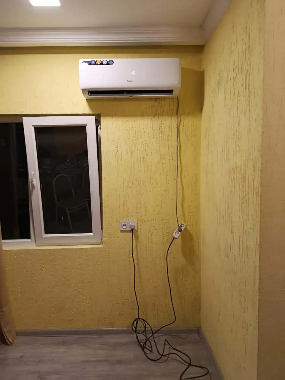 Техник по кондиционированию размещает внутренний блок кондиционера Whirlpool в Тбилиси
