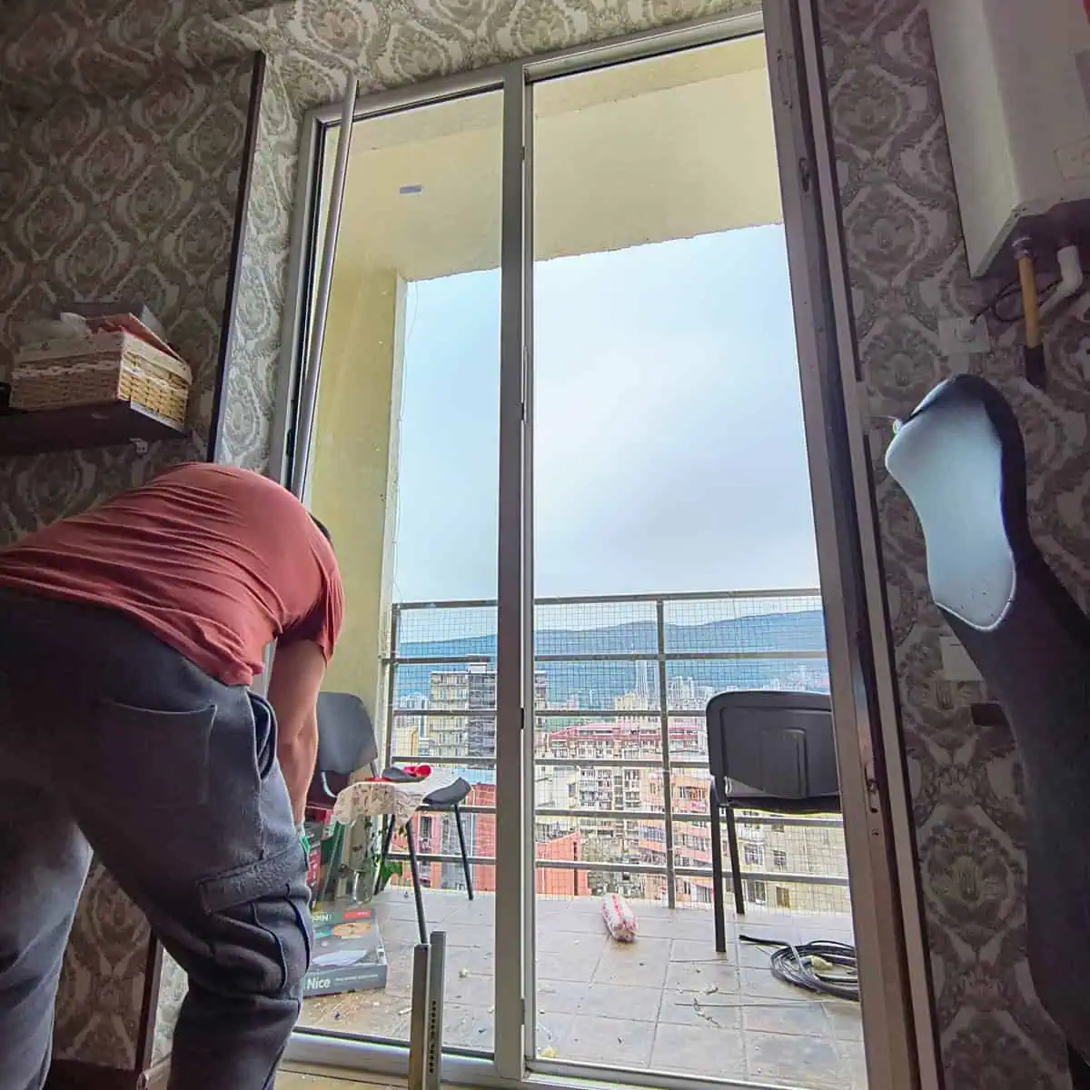 Glazing technician fitting a new unit into a balcony door in a Tbilisi apartment