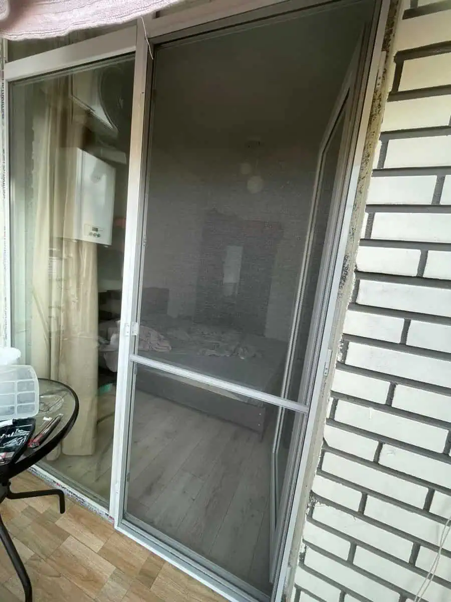 Мастер CityHandyman монтирует москитную сетку на окно в жилой квартире в Тбилиси