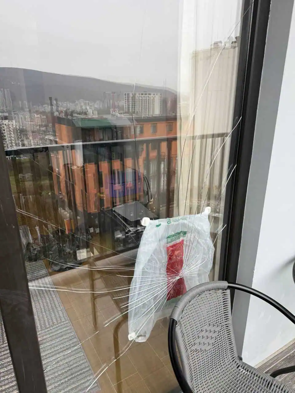 Cracked window pane with spider-web fractures in a balcony frame high-rise Tbilisi
